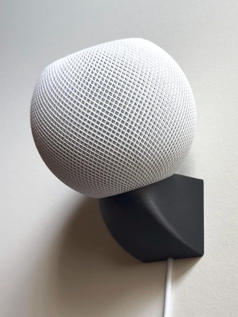 Black SPEKURA wall mount holding a white HomePod mini with the cable routed straight down