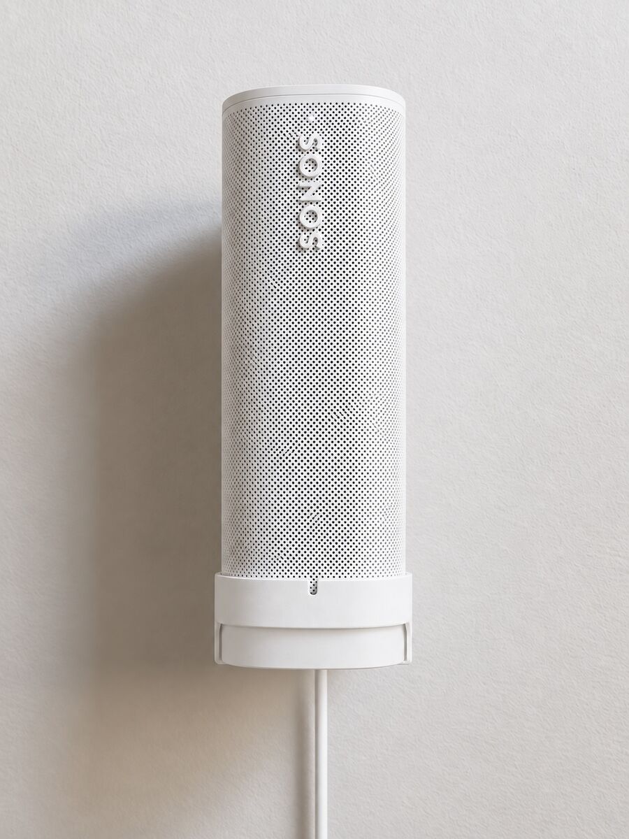 White Sonos Roam seated on the white SPEKURA charging wall mount with the white Sonos Roam Wireless Charger and power cable